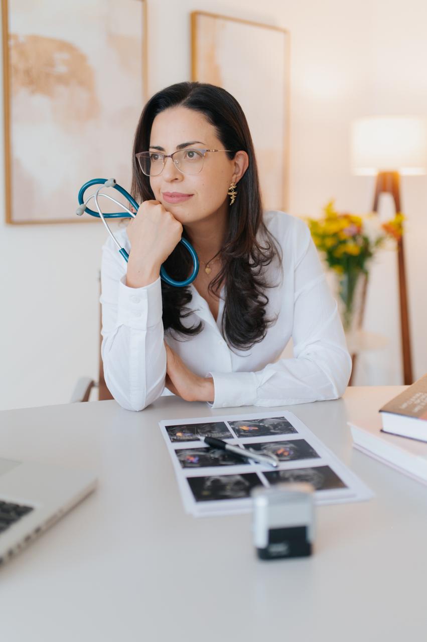 Dra. Gerusa Vilas-Bôas sentada à mesa de trabalho, com imagens de ecocardiograma à frente.